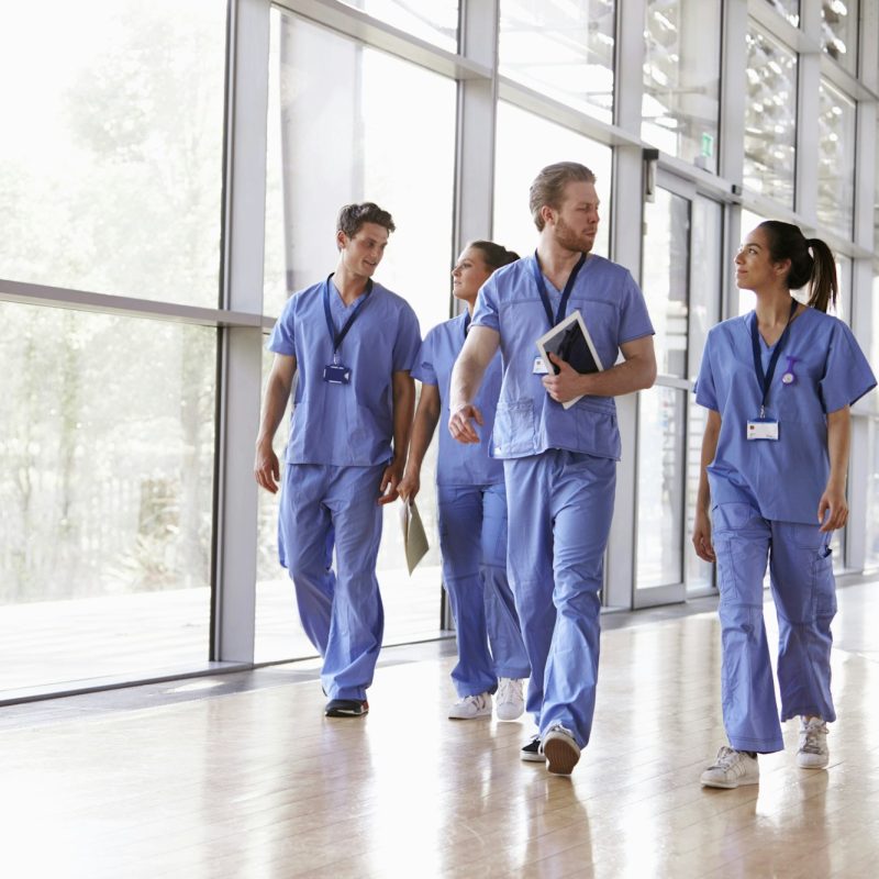 Four healthcare workers in scrubs walking in corridor